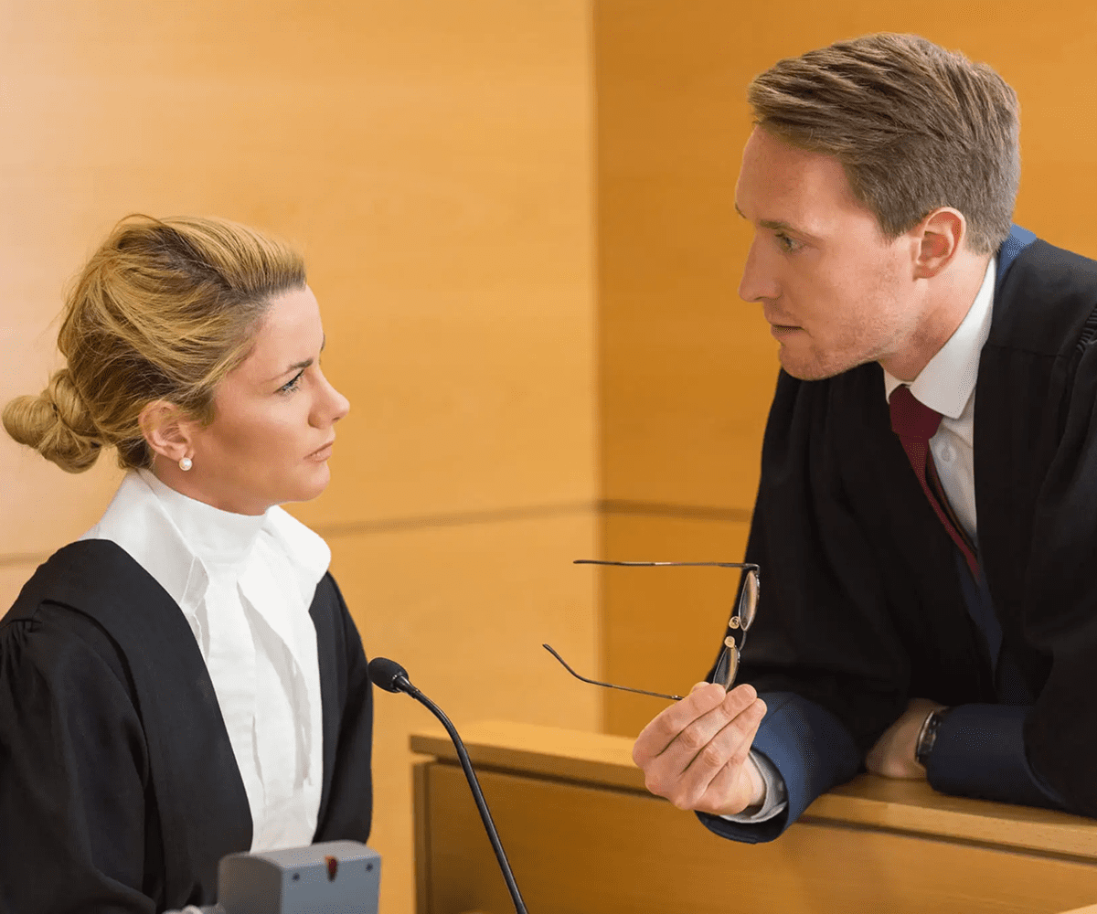 Two lawyers engaged in a serious courtroom discussion.