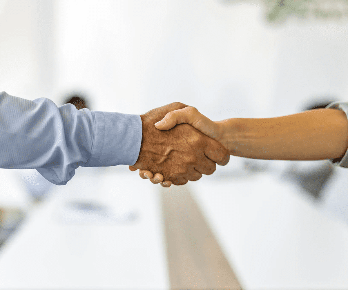 Two people shaking hands in a professional setting.