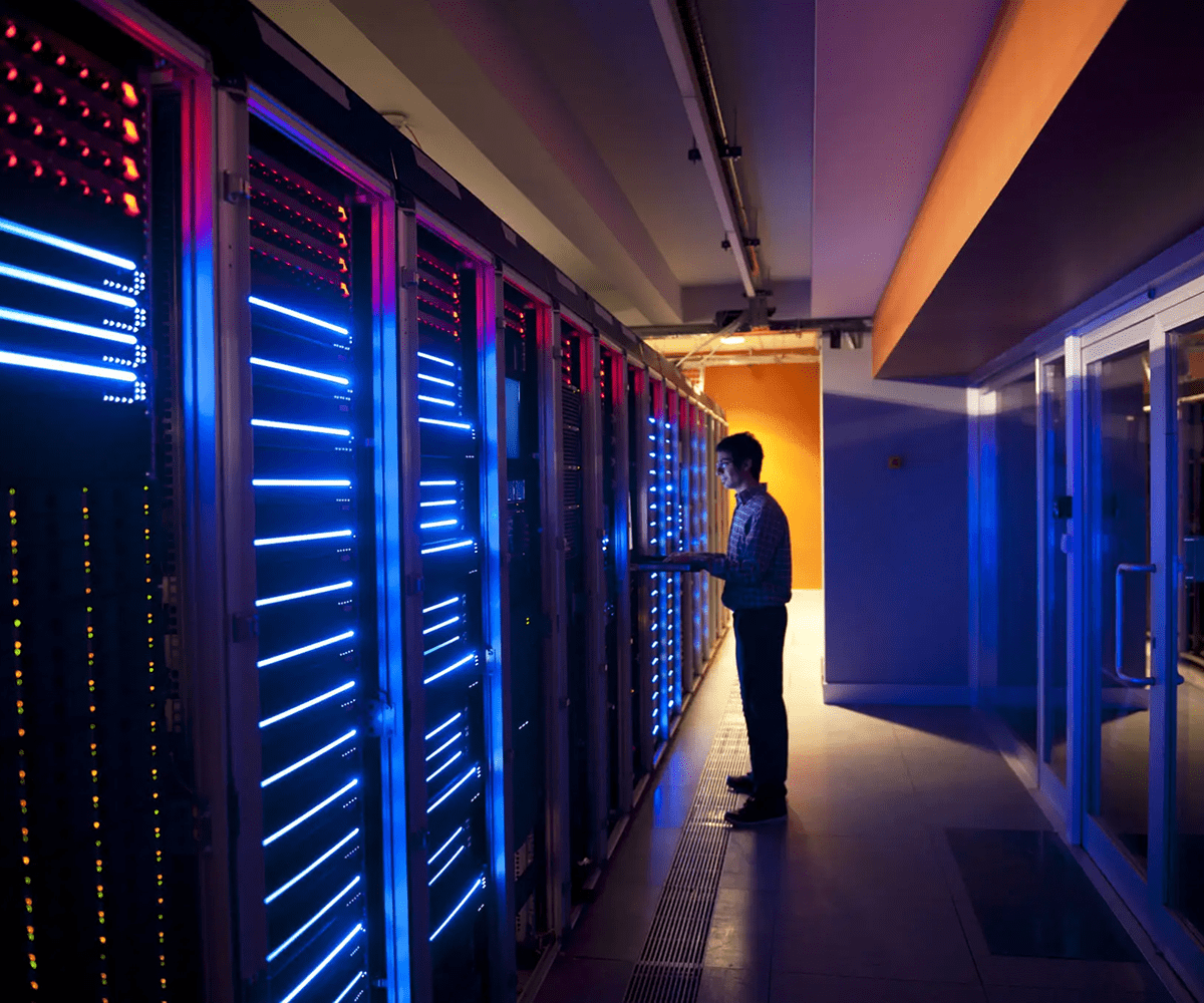 Technician working on illuminated server racks in a data center.